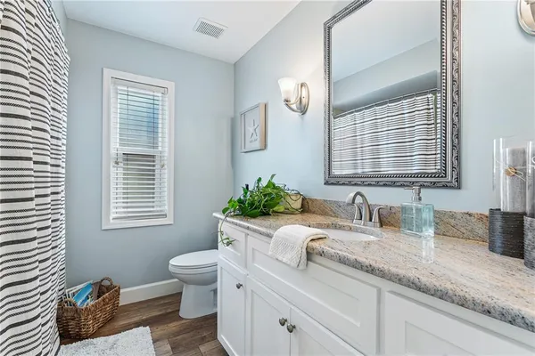 a bathroom with a granite countertop sink a toilet a mirror and a window