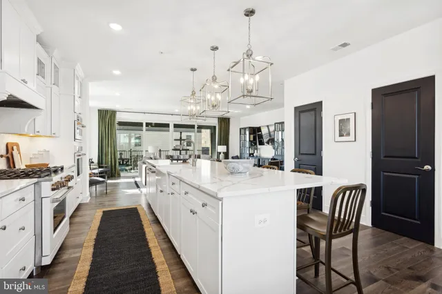 a large kitchen with stainless steel appliances kitchen island granite countertop a table chairs and a refrigerator