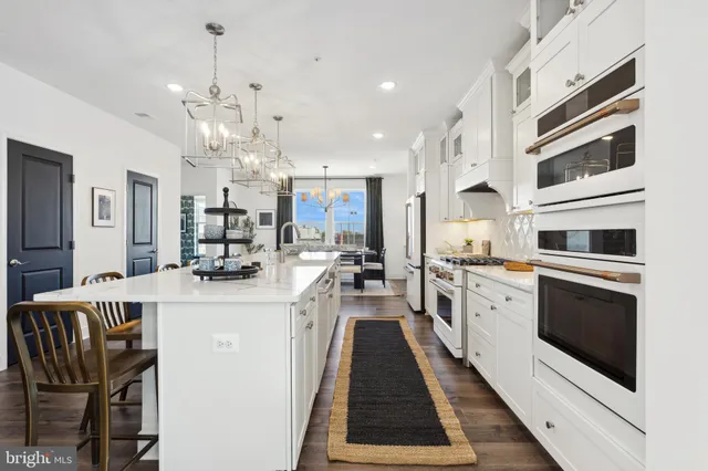 a kitchen with stainless steel appliances kitchen island granite countertop a stove top oven a sink a dining table and chairs