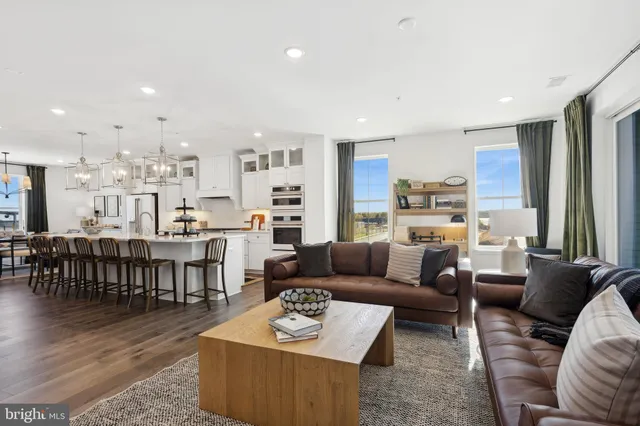 a living room with furniture kitchen view and a wooden floor