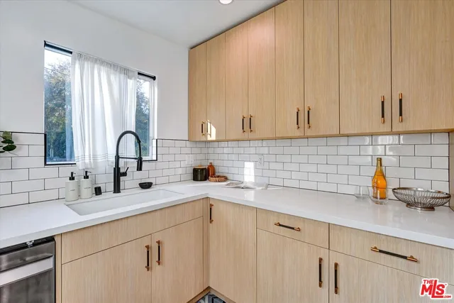 a kitchen with stainless steel appliances white cabinets a sink and a large window