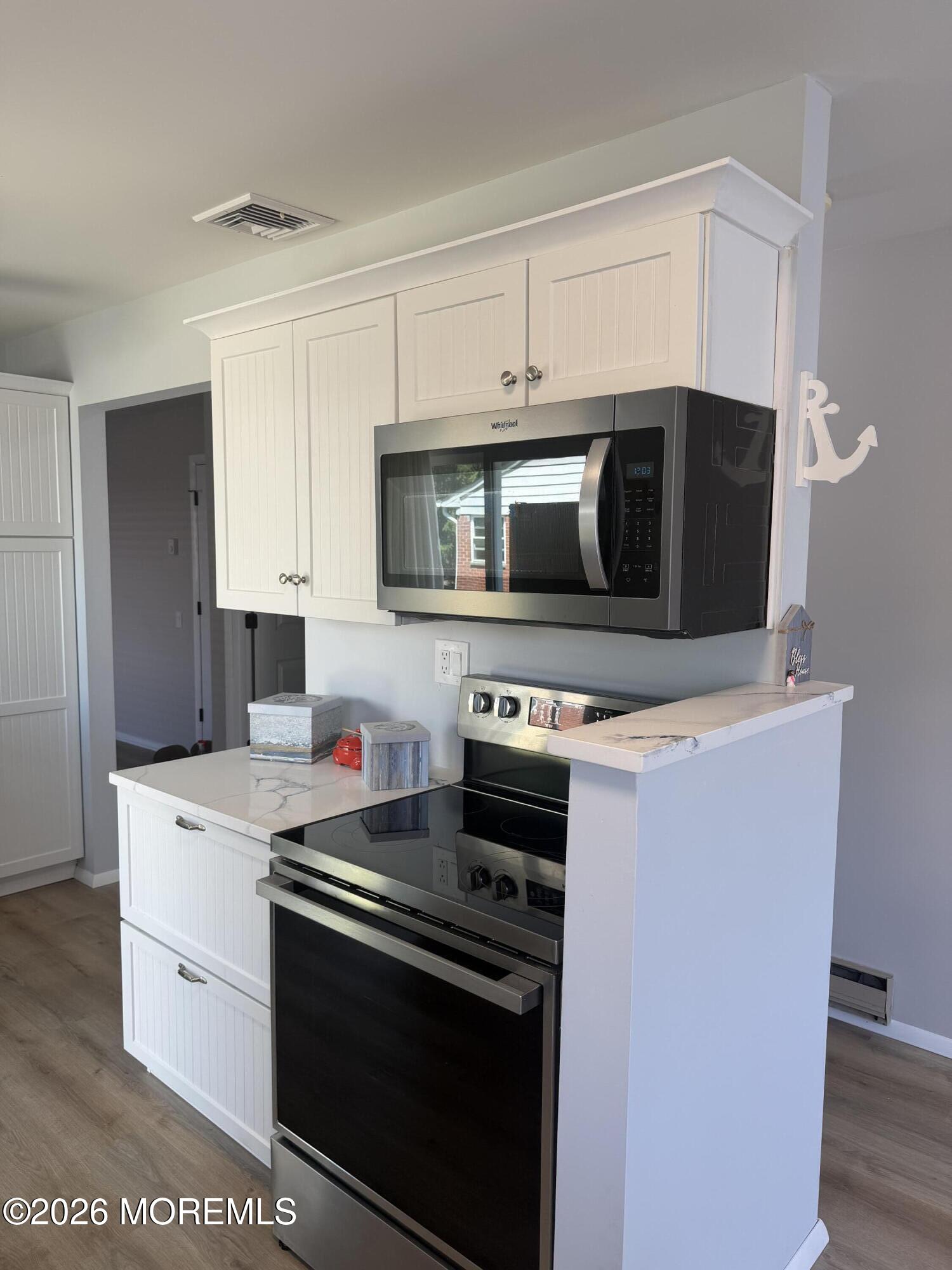 31 Homestead Drive, Unit A Whiting, NJ 08759 - Photo 11 of 23 a kitchen with stainless steel appliances a stove a microwave a sink and cabinets