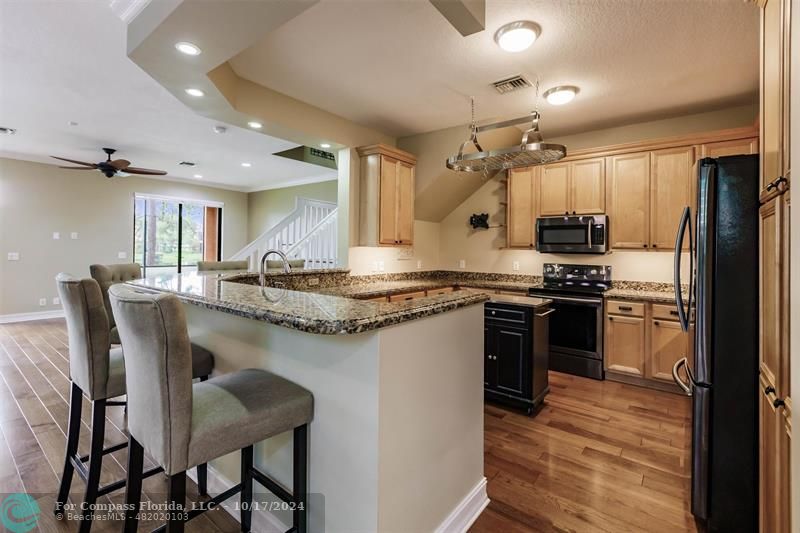 116 Southeast Crestwood Circle Stuart, FL 34997 - Photo 5 of 48 a kitchen with stainless steel appliances kitchen island granite countertop a table chairs and a refrigerator