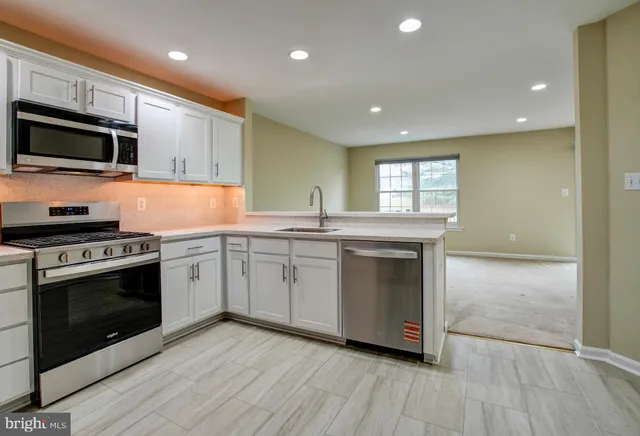 a kitchen with granite countertop a refrigerator and a stove top oven