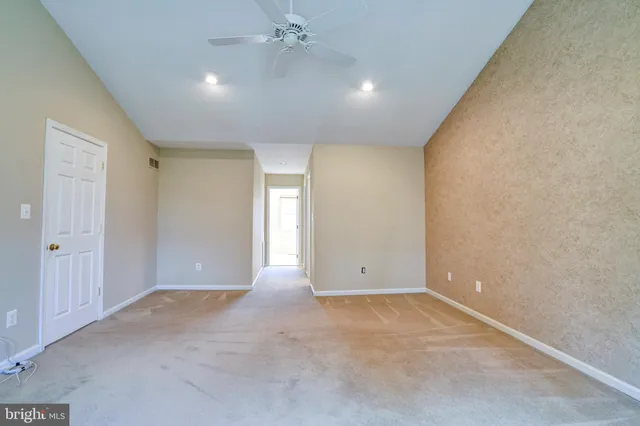 an empty room with a ceiling fan and carpet