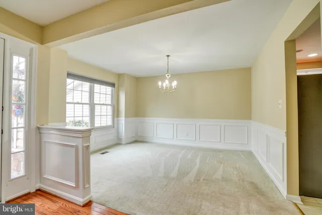 a view of an empty room with window and chandelier