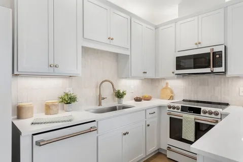 a kitchen with stainless steel appliances granite countertop white cabinets a sink and dishwasher