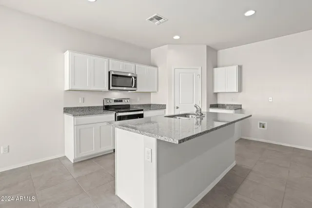 a kitchen with granite countertop a sink and a stove top oven with white cabinets