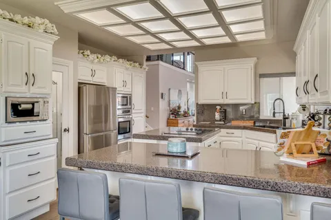 a kitchen with granite countertop a sink stainless steel appliances and white cabinets