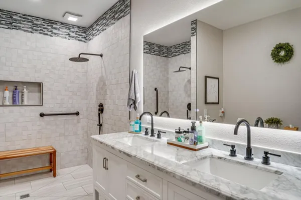 a bathroom with double vanity sinks a mirror and a shower