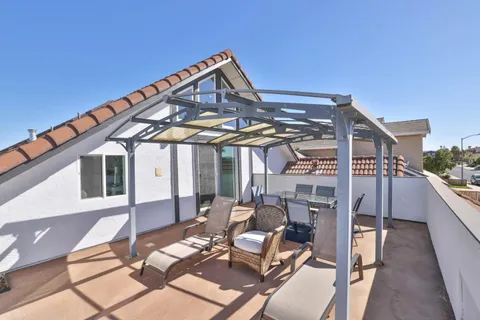a view of a patio with table and chairs near a barbeque