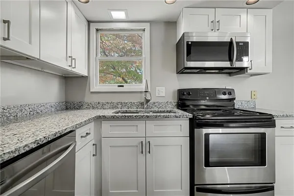 a kitchen with stainless steel appliances granite countertop white cabinets granite counter tops and a window