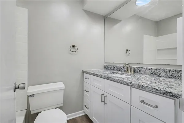 a bathroom with a granite countertop toilet sink and mirror