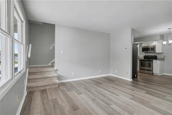 a view of a livingroom with wooden floor and kitchen space