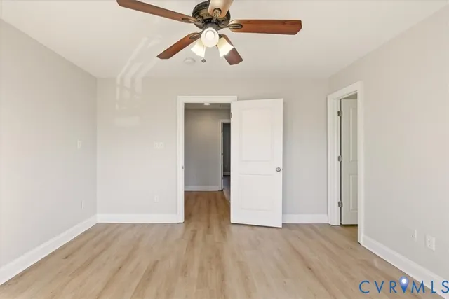 an empty room with wooden floor ceiling fan and window