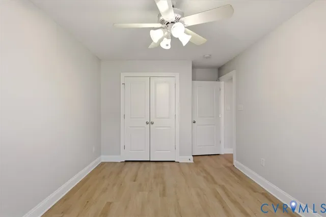 a view of an empty room with chandelier fan