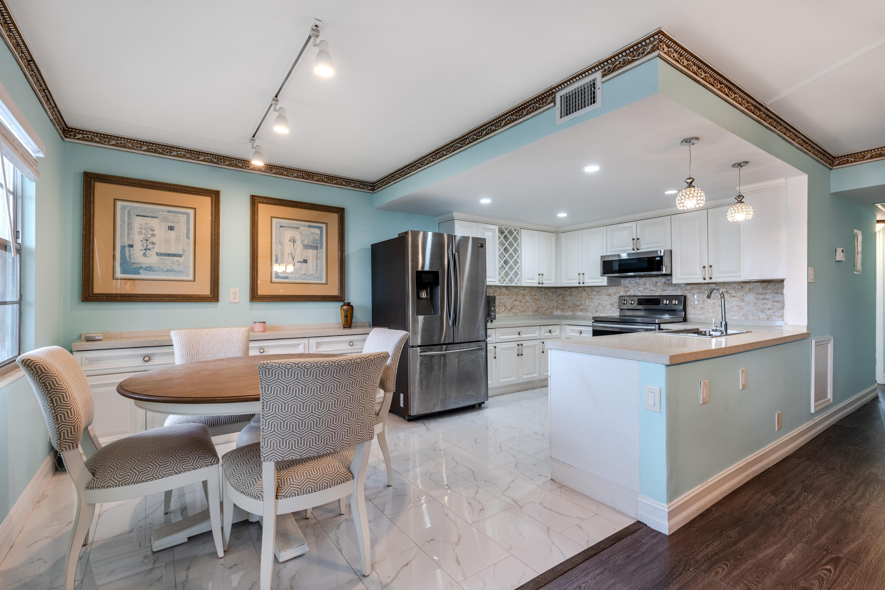 a kitchen with stainless steel appliances kitchen island granite countertop a dining table chairs microwave and sink