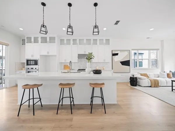 a dining hall with stainless steel appliances kitchen island granite countertop a dining table chairs and couches