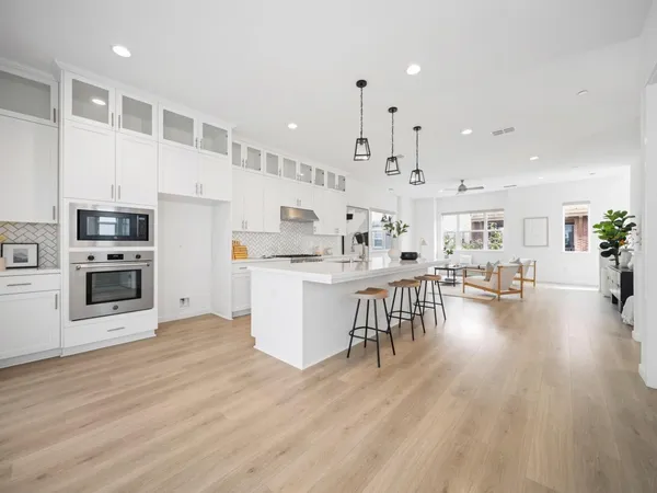 a large white kitchen with lots of counter space wooden floor and appliances
