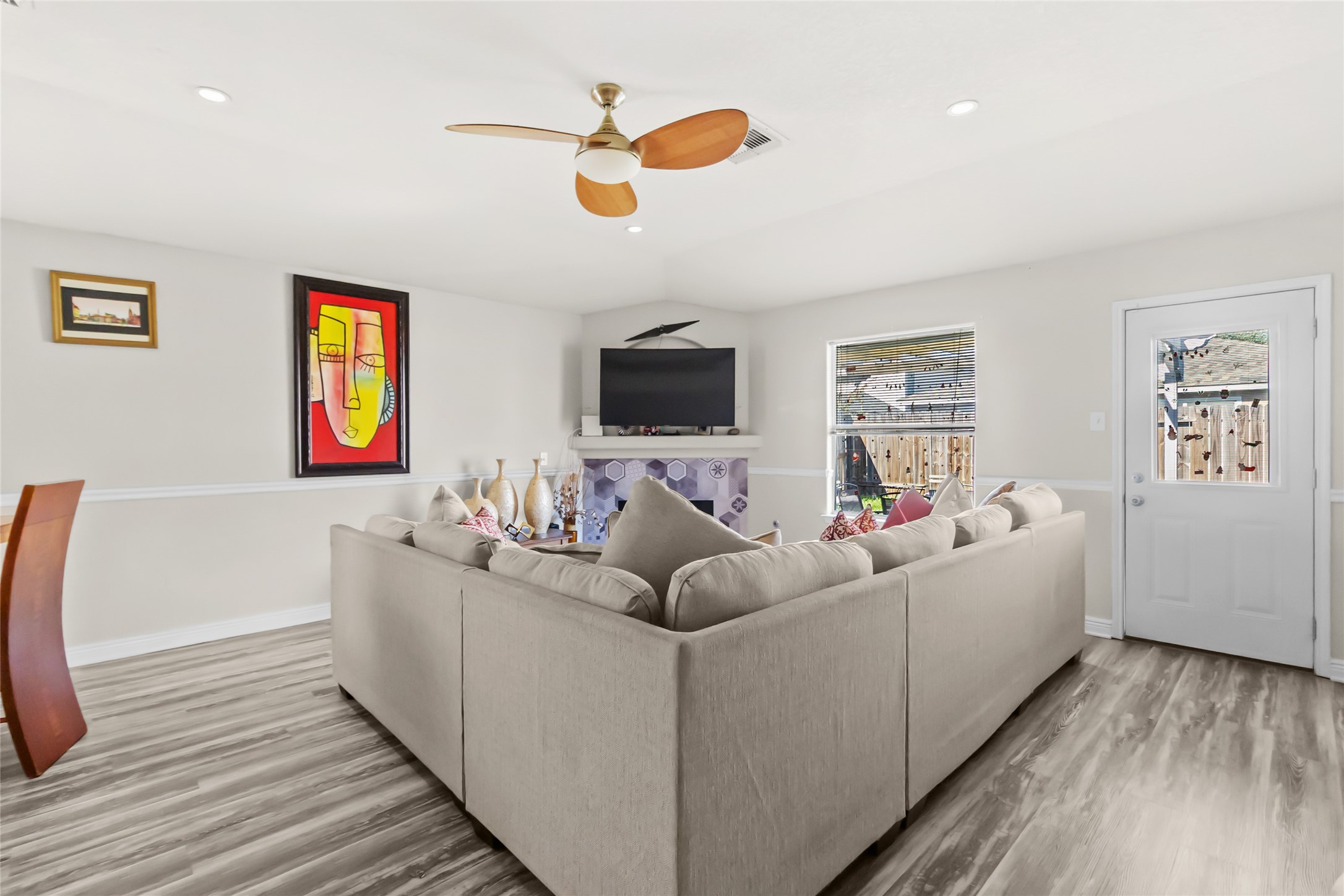 615 Ashlen Drive Houston, TX 77073 - Photo 23 of 35 You’ve got a spacious living area that’s already set up for comfort and connection, anchored by a cozy fireplace with a mounted TV—perfect for movie nights or game days. Luxury plank flooring flows throughout, while recessed lighting and a modern ceiling fan keep the space bright and comfortable. The back door and window bring in natural light and give you easy access to the backyard for indoor-outdoor living.