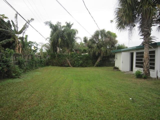 341 Shady Lane Road Palm Springs, FL 33461 - Photo 3 of 24 a backyard of a house with potted plants and palm trees