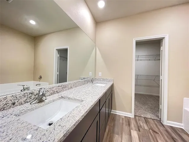 a bathroom with a granite countertop sink and a wooden floor