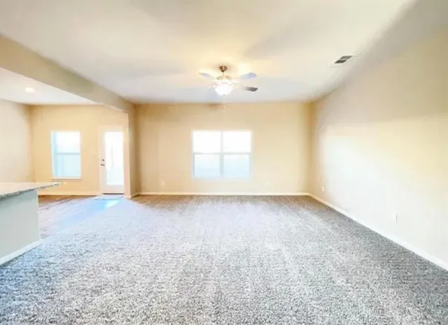 an empty room with a window and a kitchen view