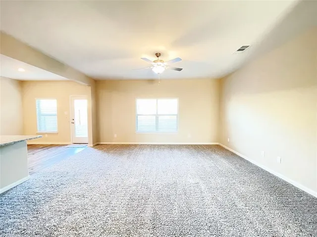 an empty room with a window and a kitchen view