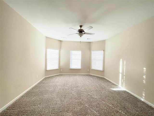 an empty room with windows and ceiling fan
