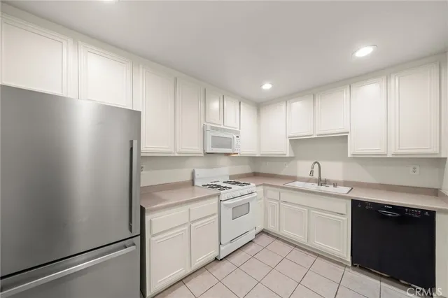 a kitchen with a sink dishwasher a refrigerator and white cabinets