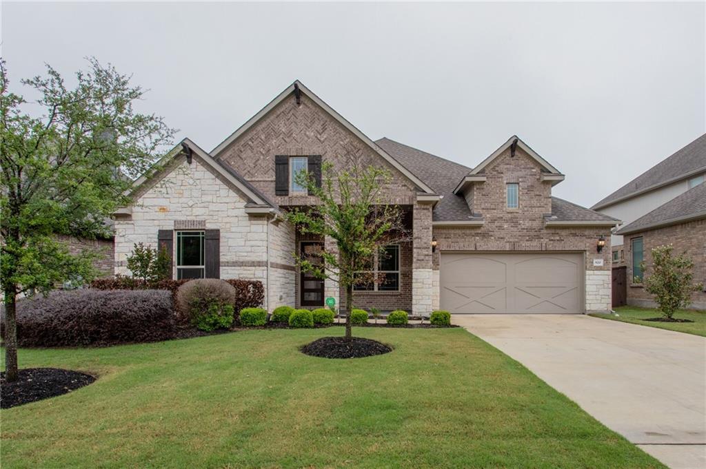 View of front facade with a front lawn, driveway, a garage, brick siding, and a shingled roof