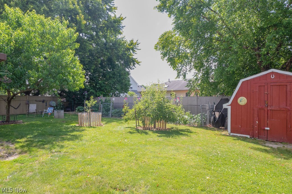 38667 Chestnut Ridge Road Elyria, OH 44035 - Photo 31 of 35 Expansive rear yard featuring a red barn-style shed with double doors, mature trees, and a wooden privacy fence