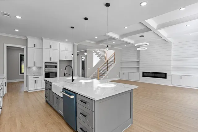 a large kitchen with stainless steel appliances kitchen island granite countertop a large kitchen island a stove a sink a refrigerator and white cabinets with wooden floor