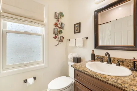 a bathroom with a granite countertop sink mirror vanity and toilet