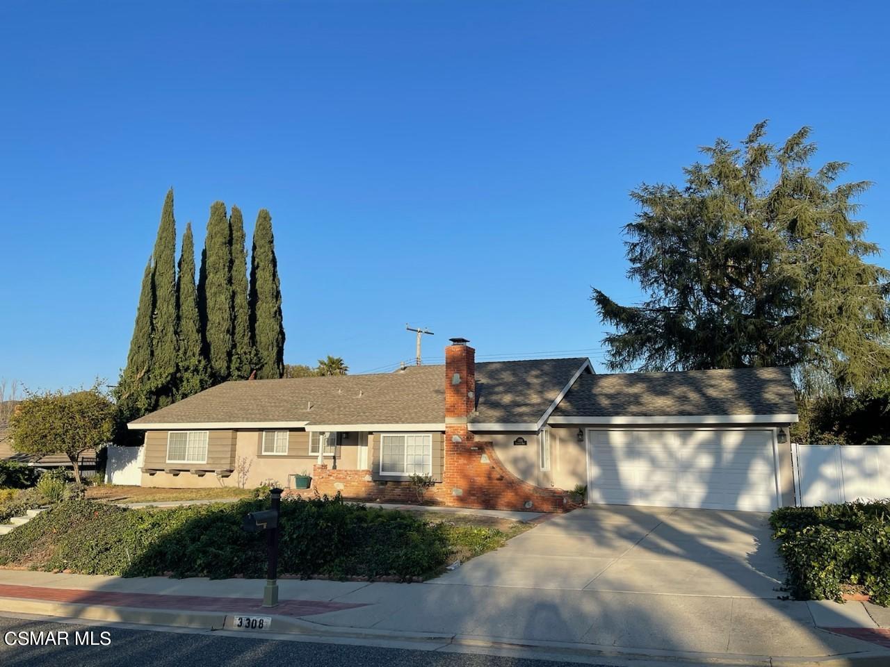 a view of a white house next to a yard with plants and trees