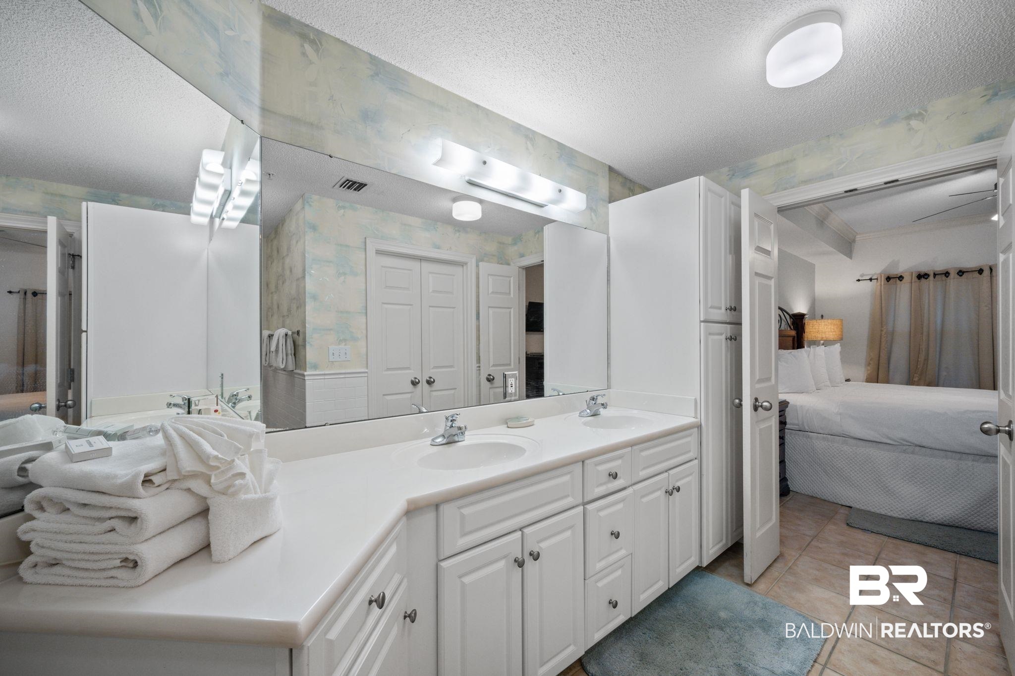 27580 Canal Road, Unit 1427 Orange Beach, AL 36561 - Photo 24 of 38 Ensuite bathroom with wallpapered walls, double vanity, a textured ceiling, light tile patterned flooring, and a closet