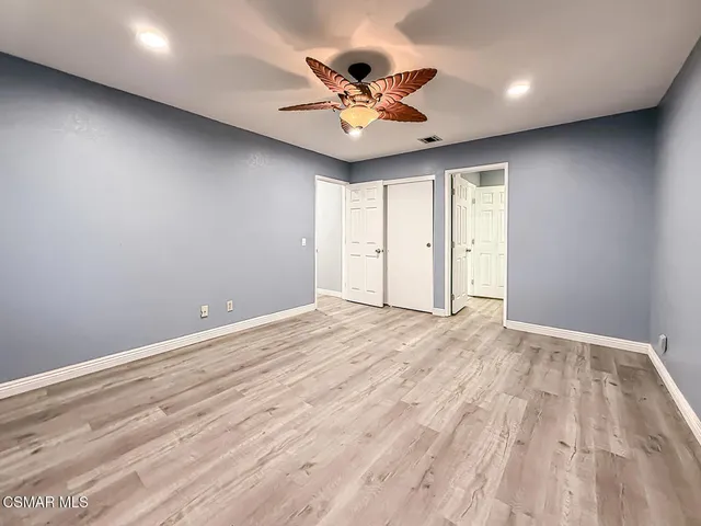 a view of a livingroom with a ceiling fan & kitchen space