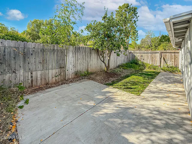 a view of small yard in front of house with wooden fence