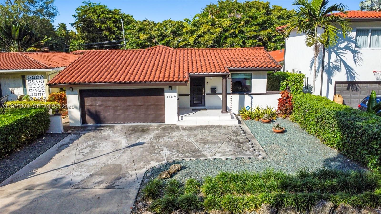 1409 Bird Road Coral Gables, FL 33146 - Photo 1 of 36 a front view of a house with a garden