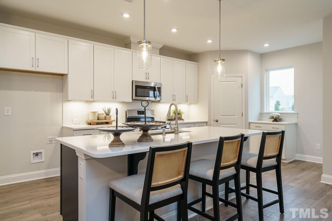 3111 Dunnock Drive, Unit 4 Durham, NC 27713 - Photo 8 of 26 a kitchen with kitchen island granite countertop a sink a center island stainless steel appliances and cabinets