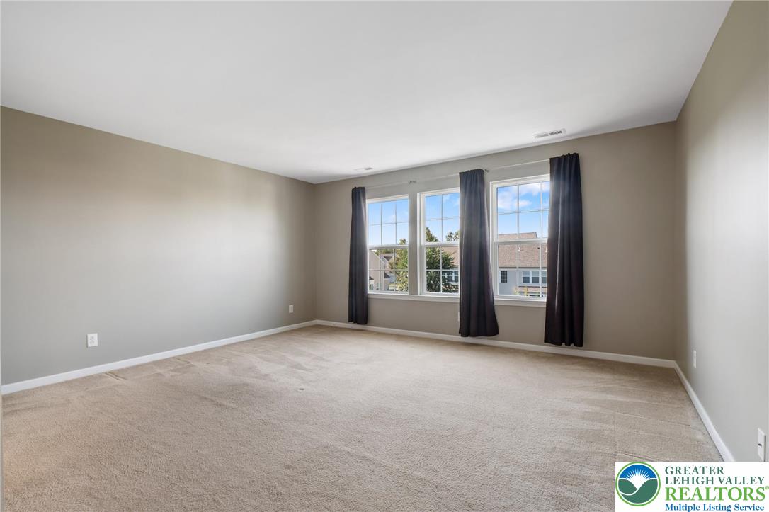 8455 Starling Road Breinigsville, PA 18031 - Photo 13 of 24 An airy primary bedroom provides ample space and three large windows overlooking the neighborhood.