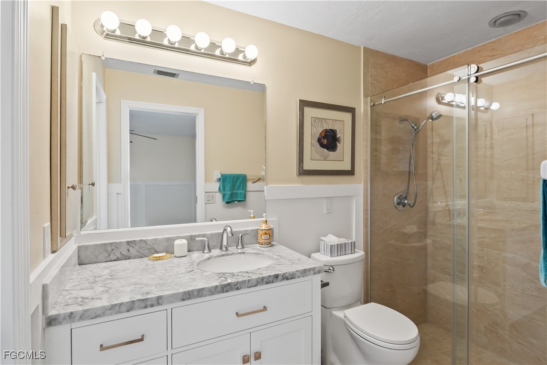 2781 Bruce Street Matlacha, FL 33993 - Photo 23 of 39 a bathroom with a granite countertop sink toilet a mirror a vanity and shower