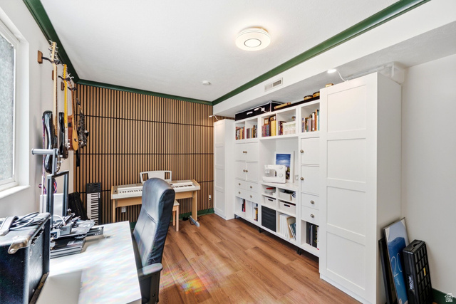 1112 Eagle Ridge Circle Sandy, UT 84094 - Photo 24 of 38 Office space with wood-finish flooring, a full wall of custom built-in cabinetry, slatted wood accent wall, and a large window