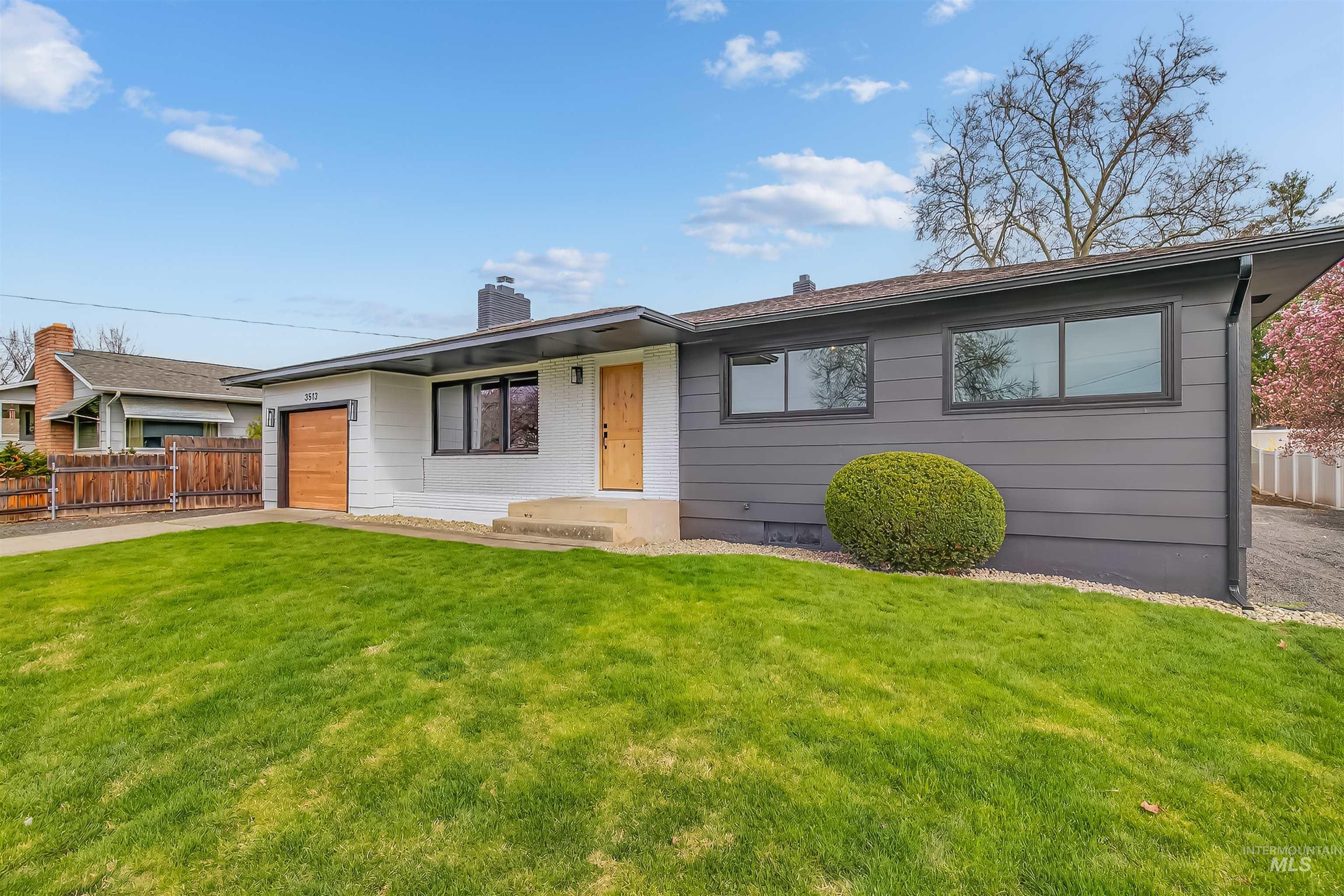 Single story home featuring a garage, a chimney, and concrete driveway