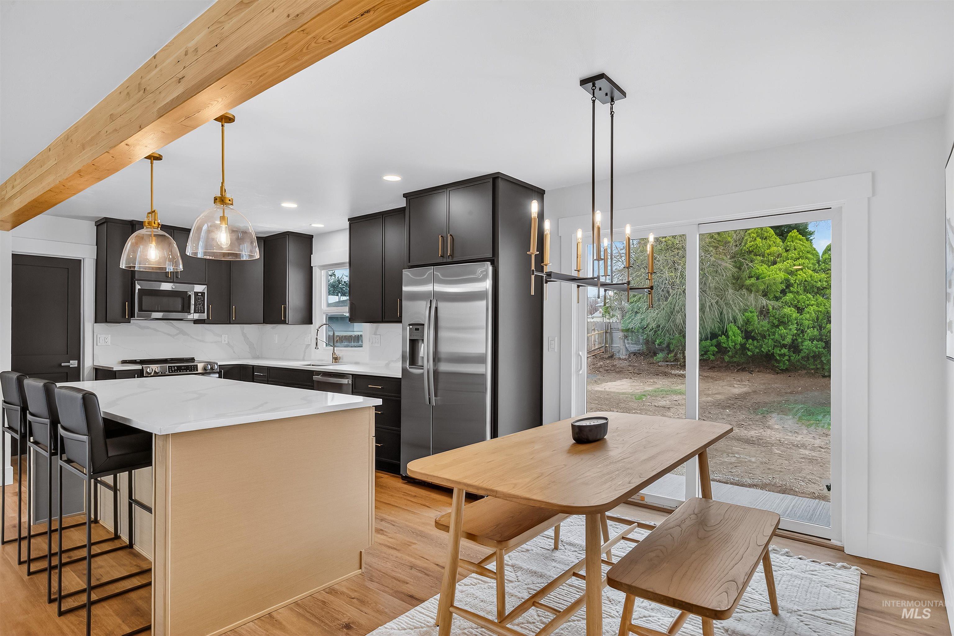 3513 8th Street Lewiston, ID 83501 - Photo 5 of 43 Kitchen featuring a breakfast bar, light wood-type flooring, a center island, stainless steel appliances, and beam ceiling