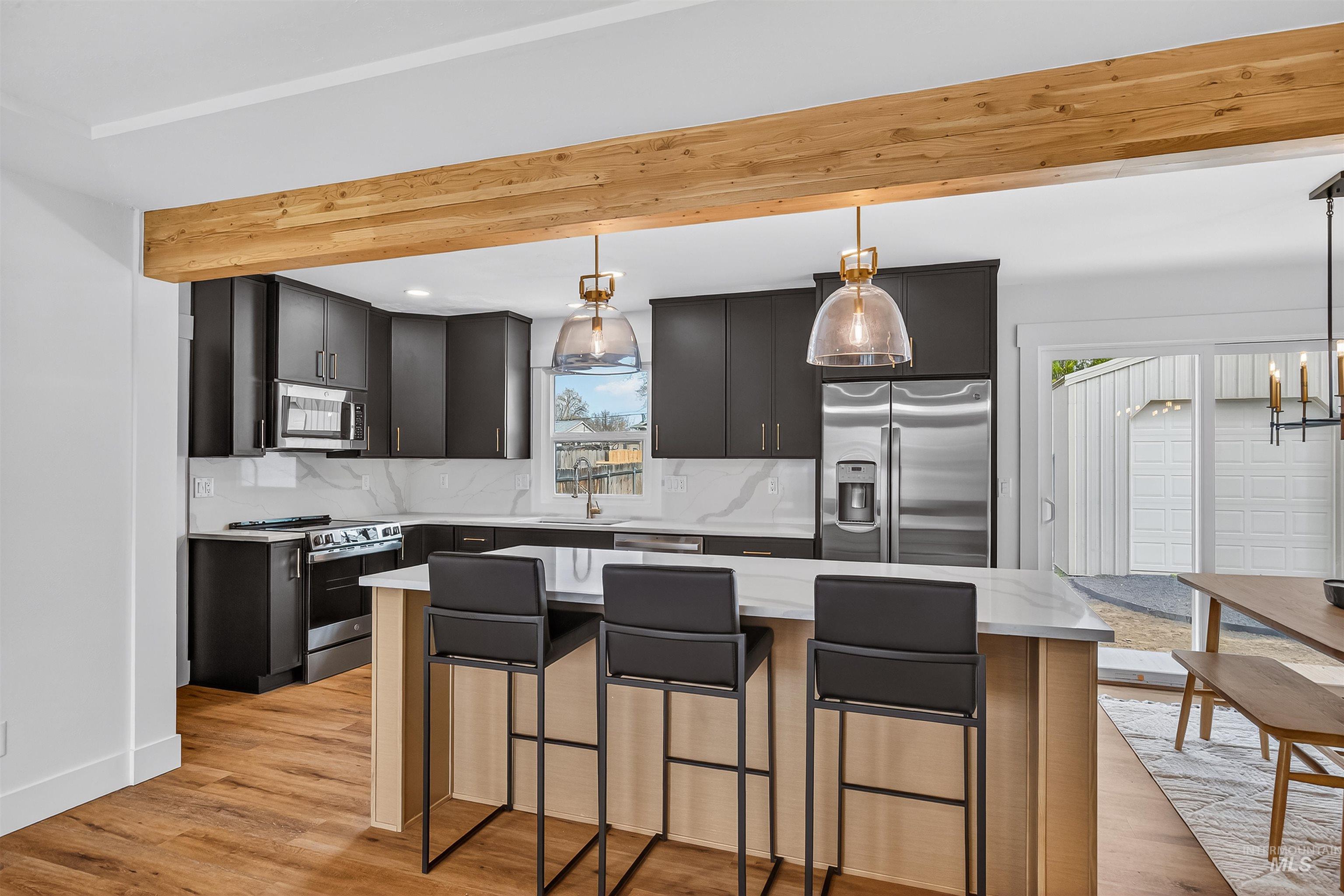 3513 8th Street Lewiston, ID 83501 - Photo 6 of 43 Kitchen featuring a kitchen island, stainless steel appliances, a kitchen breakfast bar, beamed ceiling, and backsplash