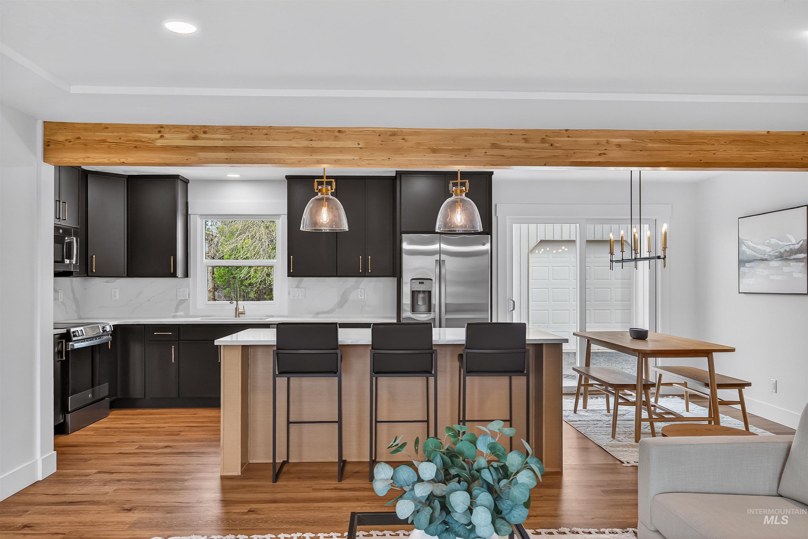 3513 8th Street Lewiston, ID 83501 - Photo 8 of 43 Kitchen featuring a kitchen island, backsplash, stainless steel appliances, light wood-type flooring, and a kitchen breakfast bar