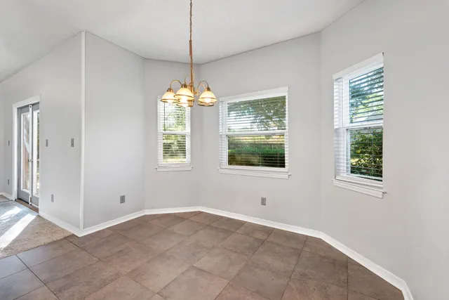 an empty room with chandelier and windows