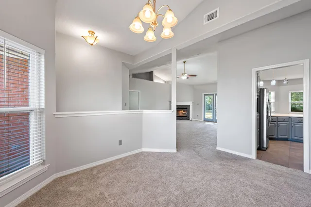 an empty room with chandelier fan and windows