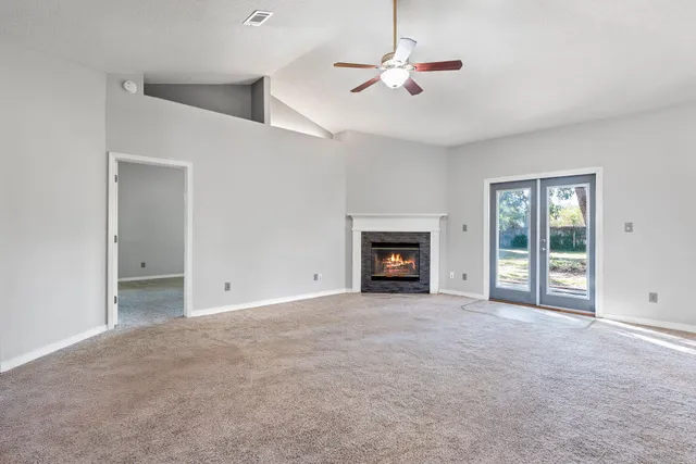 a view of an empty room with a fireplace and a window